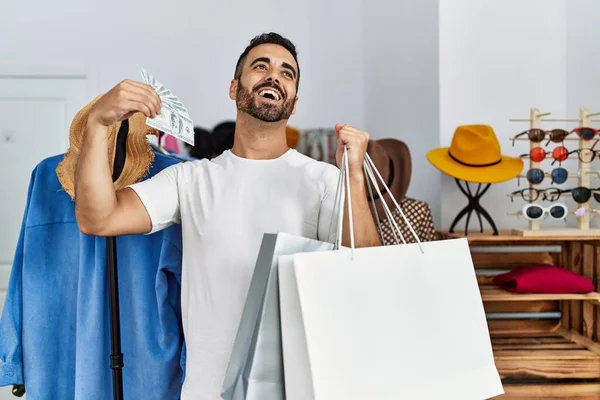 Young Hispanic Man Customer Holding Shopping Bags Faning Dollars Clothing — Stockfoto