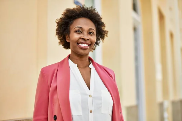 Beautiful business african american woman with afro hair smiling happy and confident outdoors at the city