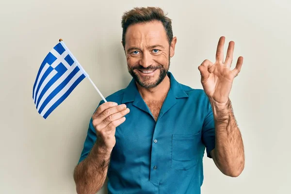 Középkorú Férfi Gazdaság Görög Zászló Csinál Rendben Jel Ujjaival Mosolygós — Stock Fotó