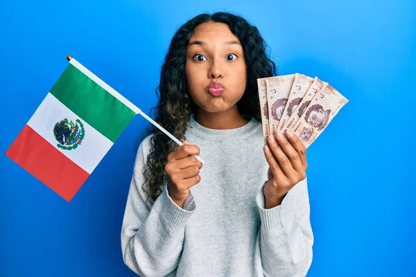 メキシコの国旗とメキシコペソの紙幣を持っている若いラテン語の女性は 面白い顔で頬をむいています 空気を吸い込み空気を吸い込み — ストック写真