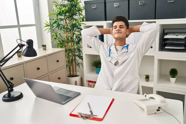 Young Hispanic Man Wearing Doctor Uniform Relaxed Hands Head Clinic — стоковое фото