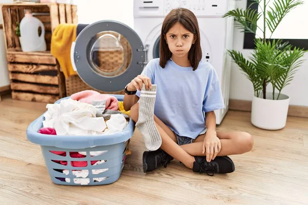 Young Hispanic Girl Doing Laundry Holding Socks Puffing Cheeks Funny — ストック写真