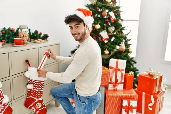 Jovem Hispânico Sorrindo Feliz Vestindo Chapéu Natal Segurando Presente Casa — Fotografia de Stock