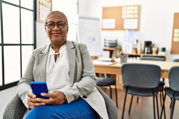 オフィスでスマートフォンを使うシニアアフリカ系アメリカ人女性ビジネスワーカー — ストック写真