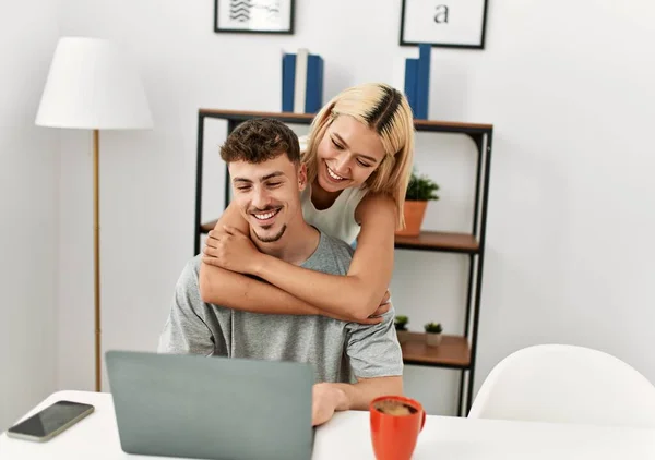 Joven Pareja Caucásica Abrazando Utilizando Ordenador Portátil Sentado Escritorio Casa —  Fotos de Stock