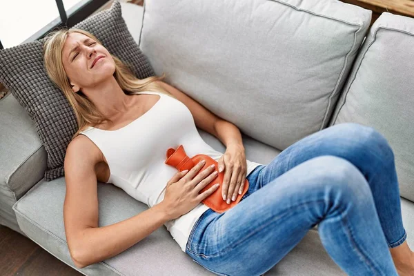 Junge Blonde Frau Leidet Unter Menstruationsbeschwerden Mit Heißem Wasserbeutel Hause — Stockfoto