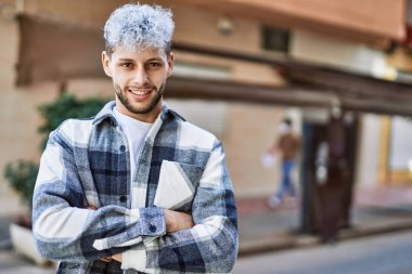 Genç İspanyol adam mutlu bir şekilde gülümsüyor şehirde çapraz hareketlerle.