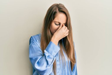 Sıradan mavi gömlek giyen genç sarışın kadın yorgun burnu ve gözleri ovuşturup yorgun ve baş ağrısı çekiyor. Stres ve hüsran kavramı. 