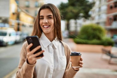 Genç İspanyol iş kadını akıllı telefon kullanıyor. Şehirde kahve içiyor..
