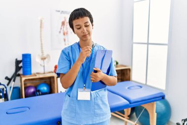 Kısa saçlı, İspanyol bir kadın ağrı kesici kliniğinde çalışıyor. Uykulu ve yorgun görünüyor. Yorgun, akşamdan kalma, tembel gözlü.. 