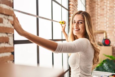 Yeni evindeki kendine güvenen sarışın kadın gülümsüyor.