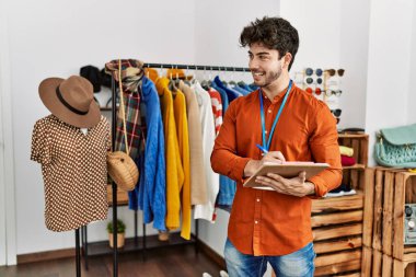 Genç İspanyol esnaf gülümsüyor. Giyim mağazasında çalışan panoya mutlu yazılar yazıyor..