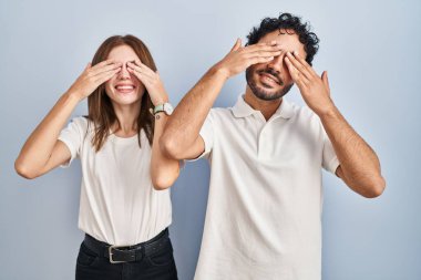 Gündelik giysiler giyen genç bir çift. Birlikte duruyorlar. Gözleri kapatıyorlar. Neşeli ve komik gülümsüyorlar. kör kavram. 