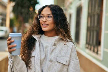 Genç Latin kadın gülümsüyor, şehirde kahve içiyor..