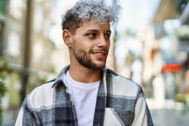 Genç İspanyol adam gülümseyerek şehirde mutlu mesut dikiliyor..