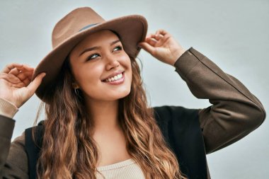 Genç İspanyol turist kadın gülümseyerek şehirde şapkasını tutarken mutlu..