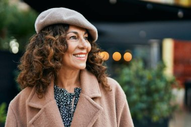 Orta yaşlı İspanyol kadın gülümseyerek şehirde mutlu mesut dikiliyor..