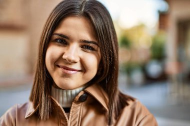 Genç, güzel, esmer kadın dışarıda mutlu bir şekilde gülümsüyor.