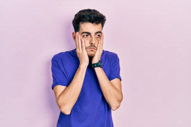 Gündelik tişört giyen genç İspanyol adam. Yorgun eller, yüzü, depresyonu ve üzüntüyü örten, sorun yüzünden üzgün ve sinirli. 