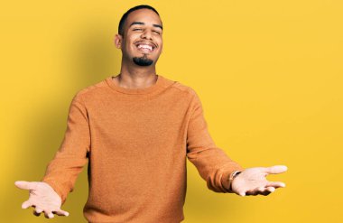 Genç Afrikalı Amerikalı günlük kıyafetler giymiş neşeli gülümseyerek yardım eli uzatıyor ve kabul ediyor.. 