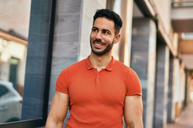 Genç İspanyol adam gülümseyerek şehirde mutlu mesut dikiliyor..