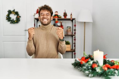 Masada sakallı yakışıklı genç bir adam başarı için heyecanlı kolları havada ve gözleri kapalı zaferi kutlarken gülümsüyor. Kazanan konsept. 