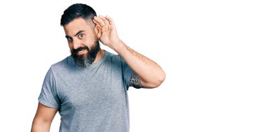 Günlük gri t-shirt giyen, ağzı kulaklarında gülümseyen ve dedikoduları ve dedikoduları dinleyen İspanyol bir adam. Sağırlık kavramı. 