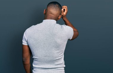 Young black man wearing casual t shirt backwards thinking about doubt with hand on head 