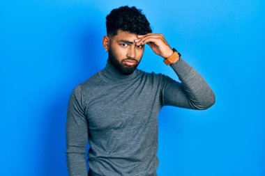 Arab man with beard wearing turtleneck sweater worried and stressed about a problem with hand on forehead, nervous and anxious for crisis 