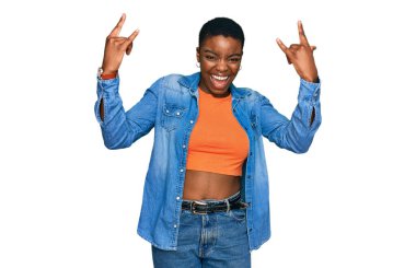 Genç Afrikalı Amerikalı kadın gündelik kıyafetler giyip çılgın bir ifadeyle bağırıyor elleri havada rock sembolü yapıyor. Müzik yıldızı. ağır müzik konsepti. 