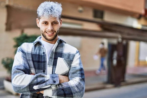 Genç İspanyol adam mutlu bir şekilde gülümsüyor şehirde çapraz hareketlerle.