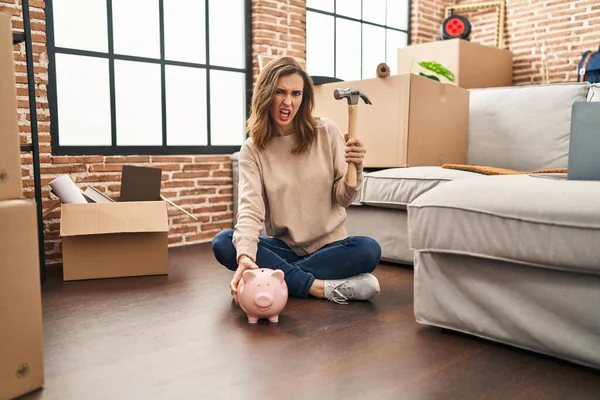 Young Woman Holding Piggy Bank Hammer Moving New Home Clueless – stockfoto