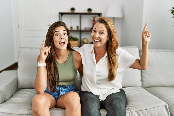 Mãe Filha Juntas Sentadas Sofá Casa Sorrindo Espantadas Surpresas Apontando — Fotografia de Stock