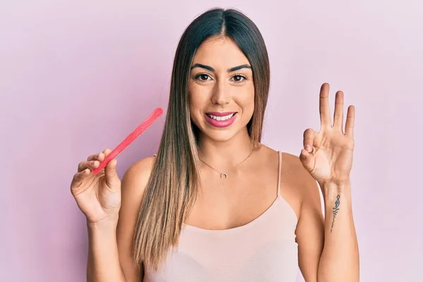 ファイルの爪を使用して若いヒスパニック系の女性は指でOkサインを行います 笑顔優しいジェスチャー優れたシンボル — ストック写真