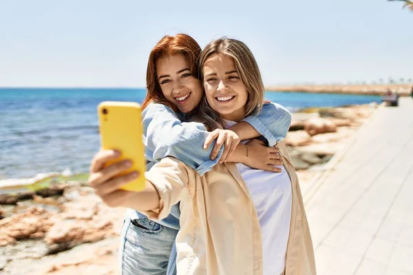 若いレズビアンビーチで恋に2人の女性のカップル スマートフォンで写真を撮るロマンチックな関係で一緒にビーチで美しい女性 — ストック写真