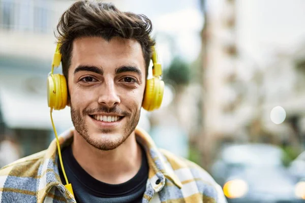 ハンサムなヒスパニック系の男笑顔幸せと自信で街で身に着けていますヘッドフォンで現代的なスタイル — ストック写真