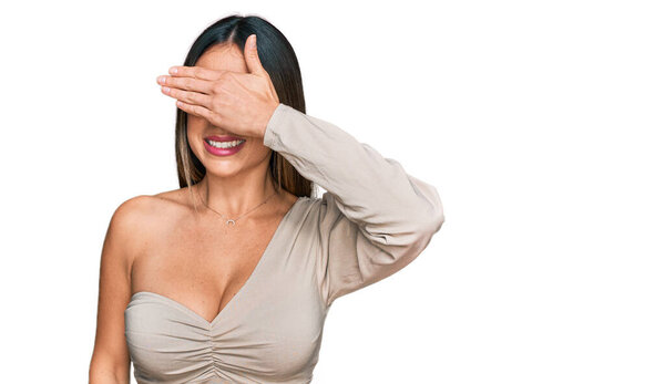 Молодая латиноамериканка в повседневной одежде улыбается и смеется, закрывая глаза рукой. слепая концепция. 