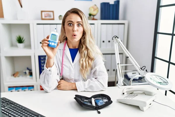 Young Beautiful Doctor Woman Holding Glucose Meter Scared Amazed Open — Foto de Stock