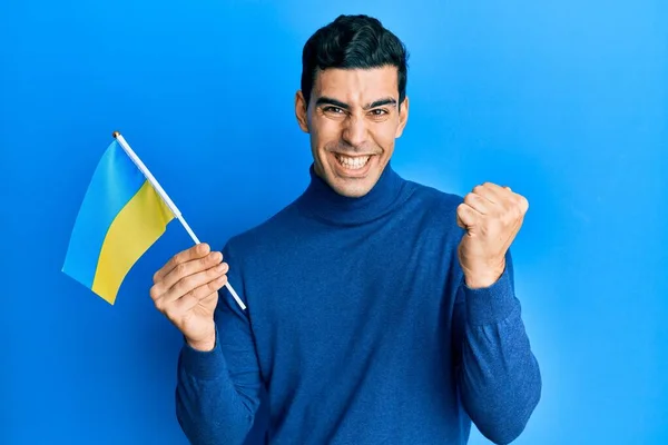 Bonito Homem Hispânico Vestindo Bandeira Ucraniana Gritando Orgulhoso Celebrando Vitória — Fotografia de Stock