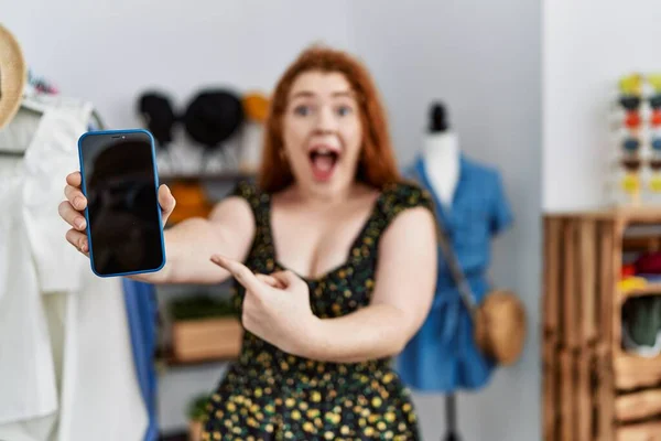 Ung Rödhårig Kvinna Butik Visar Smartphone Skärm Ler Glad Pekar — Stockfoto