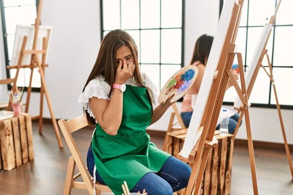 若いヒスパニック系のアーティストの女性は アートスタジオでは疲れ鼻や目をこすり疲労感や頭痛を感じるキャンバス上で絵を描く ストレスとフラストレーションの概念 — ストック写真