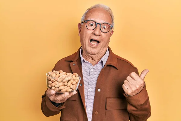 Senior Man Grey Hair Holding Peanuts Pointing Thumb Side Smiling — Fotografia de Stock