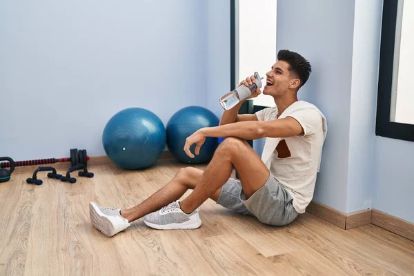 Young Hispanic Man Drinking Water Sitting Floor Sport Center — стоковое фото