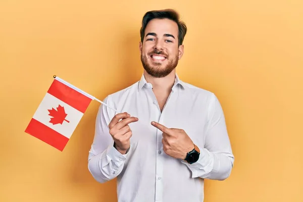 英俊的高加索男子 留着胡须 手持加拿大国旗 高兴地微笑着 手指手画脚 — 图库照片