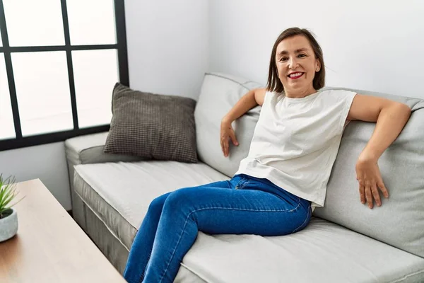 Mulher Hispânica Meia Idade Sorrindo Sentada Sofá Casa — Fotografia de Stock