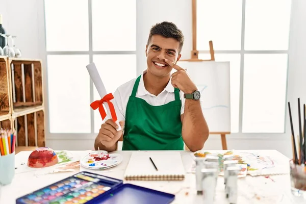 Young Hispanic Man Art Studio Holding Degree Pointing Hand Finger — Stockfoto