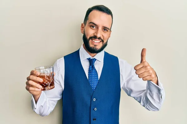 Sakallı Genç Adam Viski Içerken Mutlu Pozitif Gülümsüyor Başparmağını Kaldırıyor — Stok fotoğraf