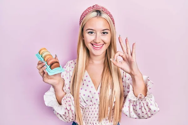 Young Blonde Girl Holding Delicious Macarons Pastries Doing Sign Fingers — Fotografia de Stock
