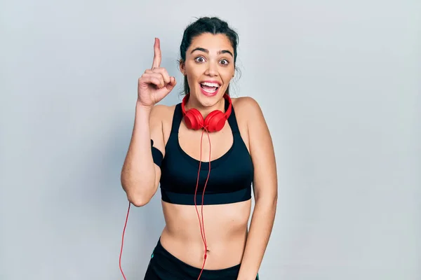 Young Hispanic Girl Wearing Gym Clothes Using Headphones Pointing Finger — 스톡 사진