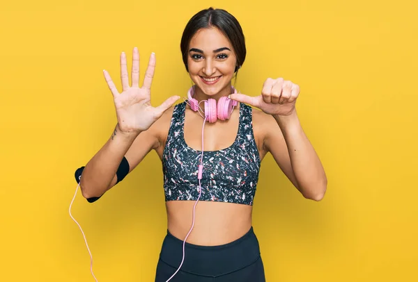 Beautiful Brunette Woman Wearing Gym Clothes Using Headphones Showing Pointing — Stok fotoğraf